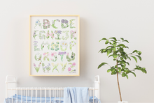 Load image into Gallery viewer, Framed alphabet print with floral designs above a crib in a nursery.