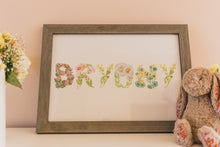 Load image into Gallery viewer, Framed artwork with floral letters spelling 'Bunny' on a light pink wall.