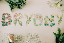 Load image into Gallery viewer, Botanical letter stickers spelling 'Bryony' arranged on a light beige surface, surrounded by green leaves, yellow flowers, and white baby's breath.