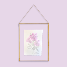 Load image into Gallery viewer, A vertical botanical art print featuring pink flowers and green leaves, displayed in a thin gold-toned frame with a hanging chain against a solid light purple background.