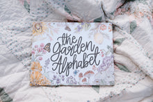 Load image into Gallery viewer, Book titled 'the Garden Alphabet' on a floral quilt