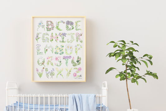 Framed alphabet print with floral designs above a crib in a nursery.