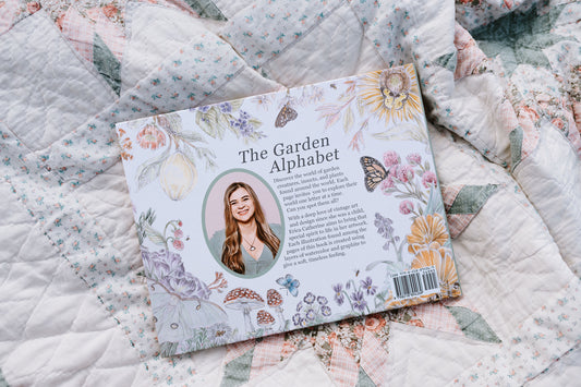 Book titled 'The Garden Alphabet' on a floral quilt