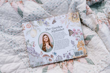 Load image into Gallery viewer, Book titled 'The Garden Alphabet' on a floral quilt
