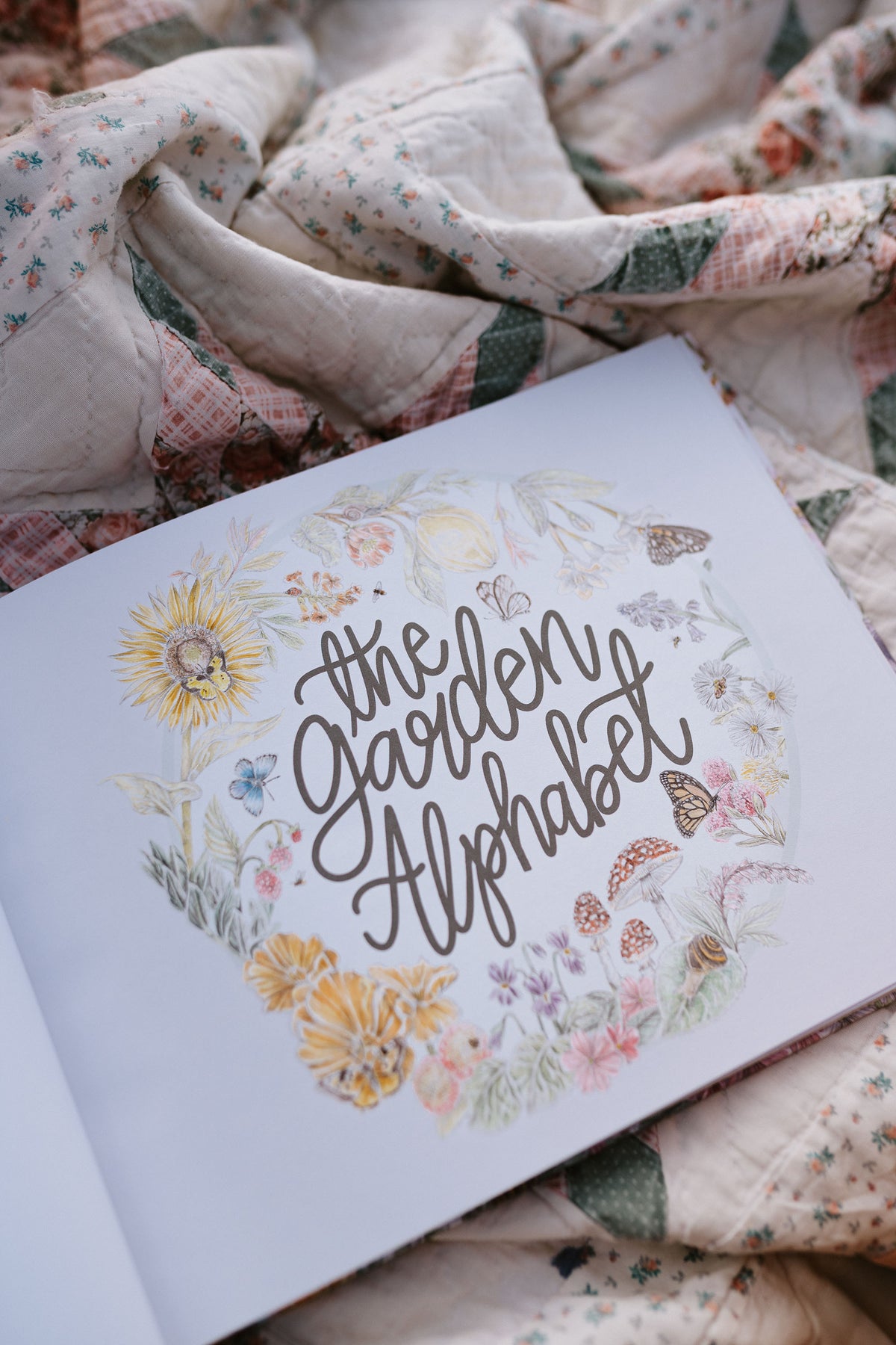 Book titled 'The Garden Alphabet' with floral designs on a floral fabric background