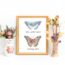 Load image into Gallery viewer, Framed butterfly print in a light wood frame with a vintage vase and dried flowers on either side. Butterfly print has two butterflies one on top of the other. The top butterfly is called the Blue spotted emperor and is a blue and white butterfly. The lower butterfly is called the mourning cloak, it is a brown butterfly with blue spots around the edge and a yellow band around the outside.
